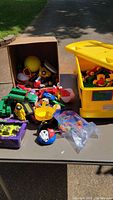 Overview of toy lot showing various toys and large yellow container with Duplo blocks