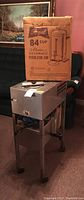 Regal 84 cup electric automatic percolator urn original cardboard box on top of the Durastill water distiller metal stand, side view