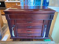 Front view of the closed wooden jewelry box with visible keys hanging from side locks.