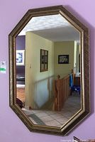 Front view of the octagonal wood framed mirror mounted on a light purple wall, showing clear reflective surface and frame details.
