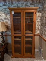 Front view of the cabinet with closed glass doors showing overall shape and finish