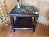 Front and side view of one wood side table with composite stone inset top, dark brown finish, and open lower shelf.