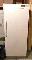 Full front view of upright freezer showing white door and handle, sealed shut.