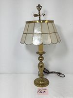 Full view of the lamp showing the brass candlestick base, capiz shell shade, and weathervane finial.