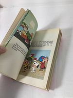 Open Peanuts book showing colorful Snoopy and friends illustration and text