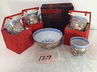 Photo showing four floral porcelain cups each in a red padded fabric box, and one scalloped porcelain bowl with floral decoration, all positioned against a white background with a lot number card.