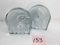Pair of clear thick heavy glass elephant-shaped bookends side by side showing front design.