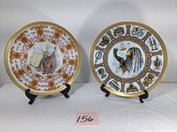 Front view of both Goebel collector plates displayed on stands, showing detailed artwork with gold trim.