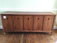 Front view of walnut veneer credenza with six paneled doors and leather pull handles
