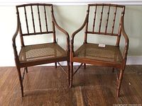 Pair of vintage Kindel chinoiserie armchairs with bamboo style wood frames and woven rattan seats, shown front and slightly angled.