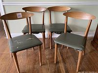 Four teak dining chairs displayed together showing overall design and condition