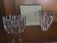 Both Orrefors crystal vase and bowl displayed on wood shelf next to Orrefors branded box