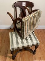 Photo of the wooden chair from the side with upholstery removed from the backrest, showing wood details and striped bench underneath.