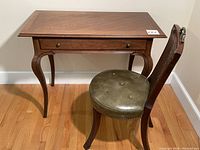 Desk and chair side view showing queen anne legs and green patent leather seat with rattan back