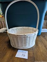 White oval medium basket with a sturdy handle, made with wide woven strips, in white color.
