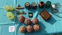 Full lot including candle holders, wicker balls, decorative ornaments, suitcase, and sentiment stone displayed on blue cloth.