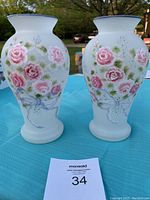 Front view of the two smokey white glass vases featuring pastel pink roses and green leaves in a floral pattern, with the matching blue rim.