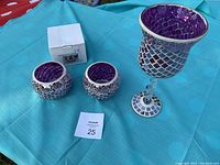 Set of three pink glass mosaic candle holders shown together on blue tablecloth, including two small round holders and one tall stemmed holder.
