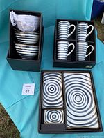 Overview photo of complete set with boxes, showing mugs, bowls, and plates with swirl blue decoration