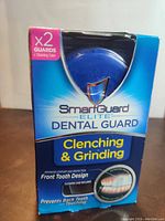 Packaging of the SmartGuard Elite dental guard highlighting product features and front tooth design to prevent clenching and grinding.
