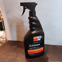 Front view of black plastic spray bottle of K&N Performance+ Home Air Filter Cleaner showing label and trigger nozzle.