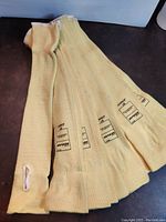 Six yellow Kevlar knit protective sleeves arranged side-by-side on a dark surface, showing length and thumb loop openings