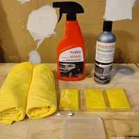 Clay bars, detailer bottles, microfiber towels, and clay bar case arranged on wood surface