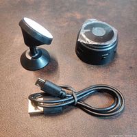 Mini camera, magnetic stand, and USB cable laid flat on surface.