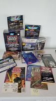 1960s-1990s Star Wars collectibles including three Micro Machines vehicles boxed (AT-AT, Millennium Falcon, one unknown), trading card sets, comic books, magazines, and AT-AT model kit boxed, shown on table.