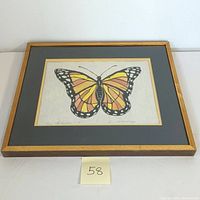 Framed butterfly lithograph on wall side angle showing overall artwork and frame
