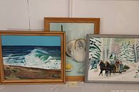 Three oil paintings shown together: seascape with wave, still life with teapot and lemon, winter scene with horse-drawn sleigh