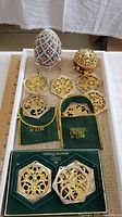 Overall lot of jeweled egg trinket box, six gold-tone 12 Days of Christmas ornaments in two green velvet pouches, and smaller round bejeweled trinket box