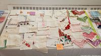 Full view of vintage handkerchiefs, linen napkins, and doilies showcasing various sizes, embroidery, and crochet work.