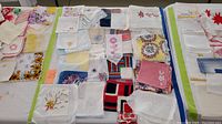 Top-down view of assorted vintage handkerchiefs, linen napkins, and doilies laid out on a table showing various embroidered and crocheted designs.