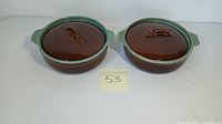 Pair of round vintage casseroles with lids from Zanesville Ohio Pottery, Country Fare series, brown and green glaze, showing light utensil marks.