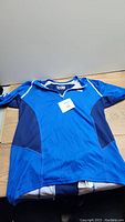 Front angled view of the blue Haley Hansen athletic shirt showing the zipper neckline and mesh panels