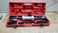 Open red hard plastic carrying case showing neatly arranged dent pull kit contents including metal pulling arms, glue gun, hammer tool, glue sticks, and pulling tabs.