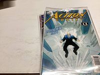Photo showing top comic book in the lot, an Action Comics issue featuring a character in a suit surrounded by ice.