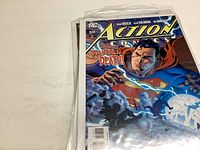 Photo showing the pile of bagged DC Action Comics issues, top issue featuring Superman with tagline 'Faith or Death'