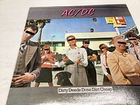 Front cover of the AC/DC 'Dirty Deeds Done Dirt Cheap' album, showing the band members posing outdoors.