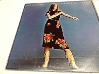 Front cover of Emmylou Harris 'Evangeline' vinyl record album showing Emmylou in floral skirt and fringed boots.