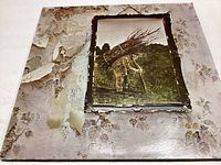 Photo of the front cover of Led Zeppelin IV album showing a man carrying sticks against a peeling wall background.