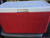 Closed view of the red and white Coleman cooler showing the exterior with no cracks and the brand embossed.
