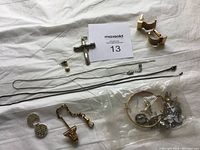 Multiple pieces including cross pendant, chain necklace, bracelet, a single earring, and a small bag with assorted charms and earrings.