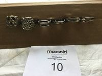 Set of six silver tone rings laid out in a row on a brown surface with MaxSold label visible.