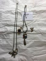 Five pieces of jewelry including pendants and a ring, laid out on white fabric, clear view of eagle motifs and stones.