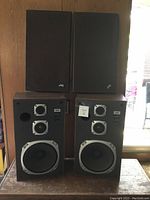 Front view of two JVC SK-202 speakers, one with cover on and one without, showing speaker drivers.