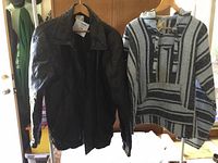 Full view of men's black leather coat on hanger besides wool pullover
