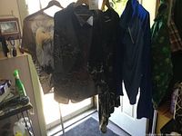 Photo shows five men's button-up shirts hanging on hangers with visible designs including eagle graphic and Asian-inspired symbols.