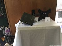 Swivel TV wall mount bracket and indoor TV antenna on a white table cover, wooden background.